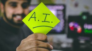Man holding green post-it note with "AI" for artificial intelligence