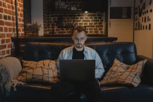 Man sitting on couch working on laptop